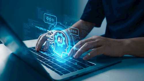 A photograph of an anonymous person typing on a laptop, above their hands on the keyboard hovers a graphic illustration suggesting AI, which shows the letters AI in side the outline of a head, with motherboard digital iconography extending from it in pale blue and white